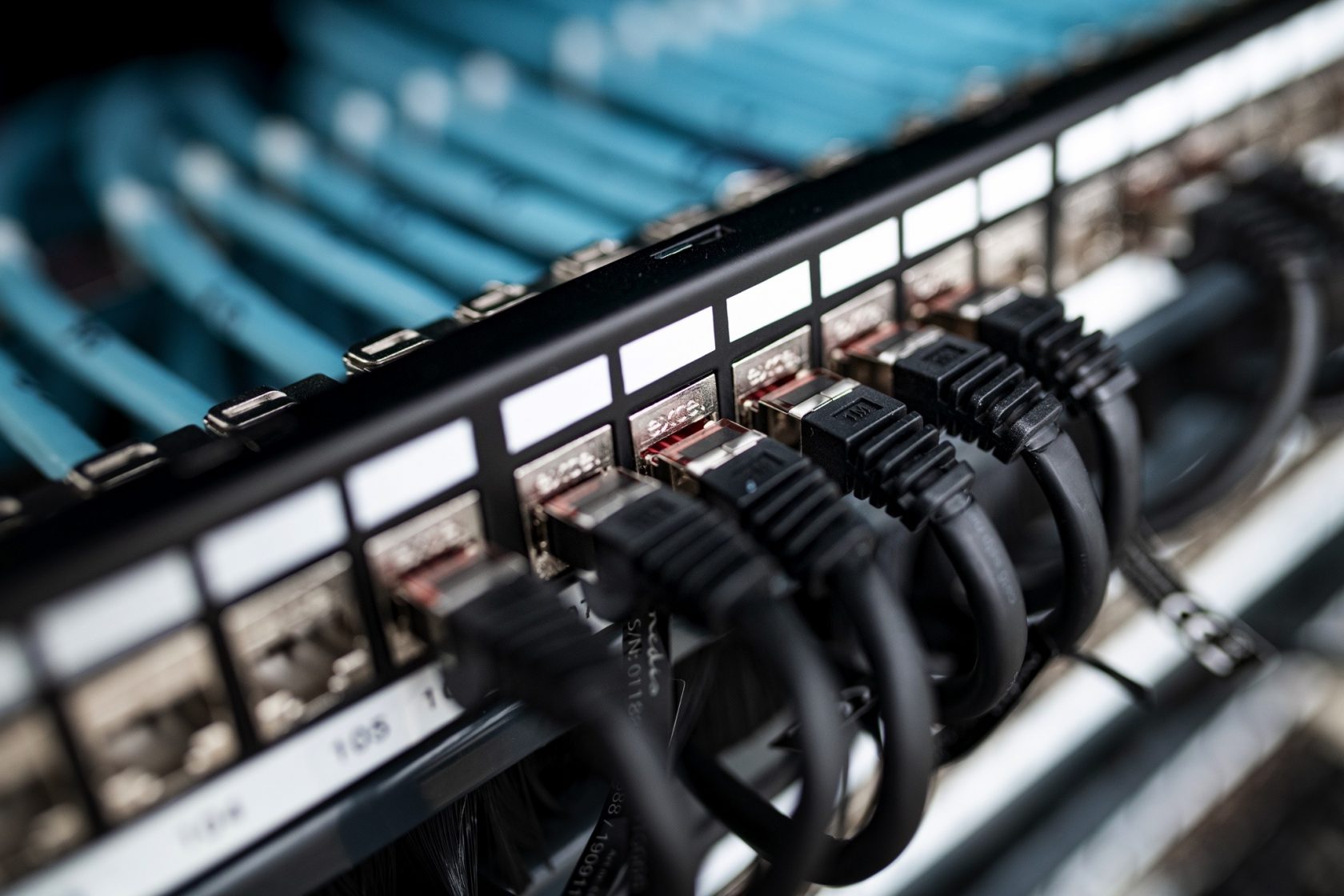 Un gros plan sur une baie informatique avec plusieurs câbles Ethernet connectés à un panneau de brassage.