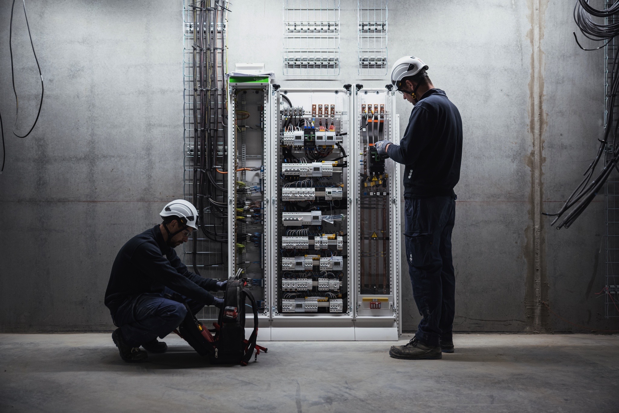 Techniciens réalisant le câblage et la mise en service d’une armoire électrique industrielle dans un local technique.