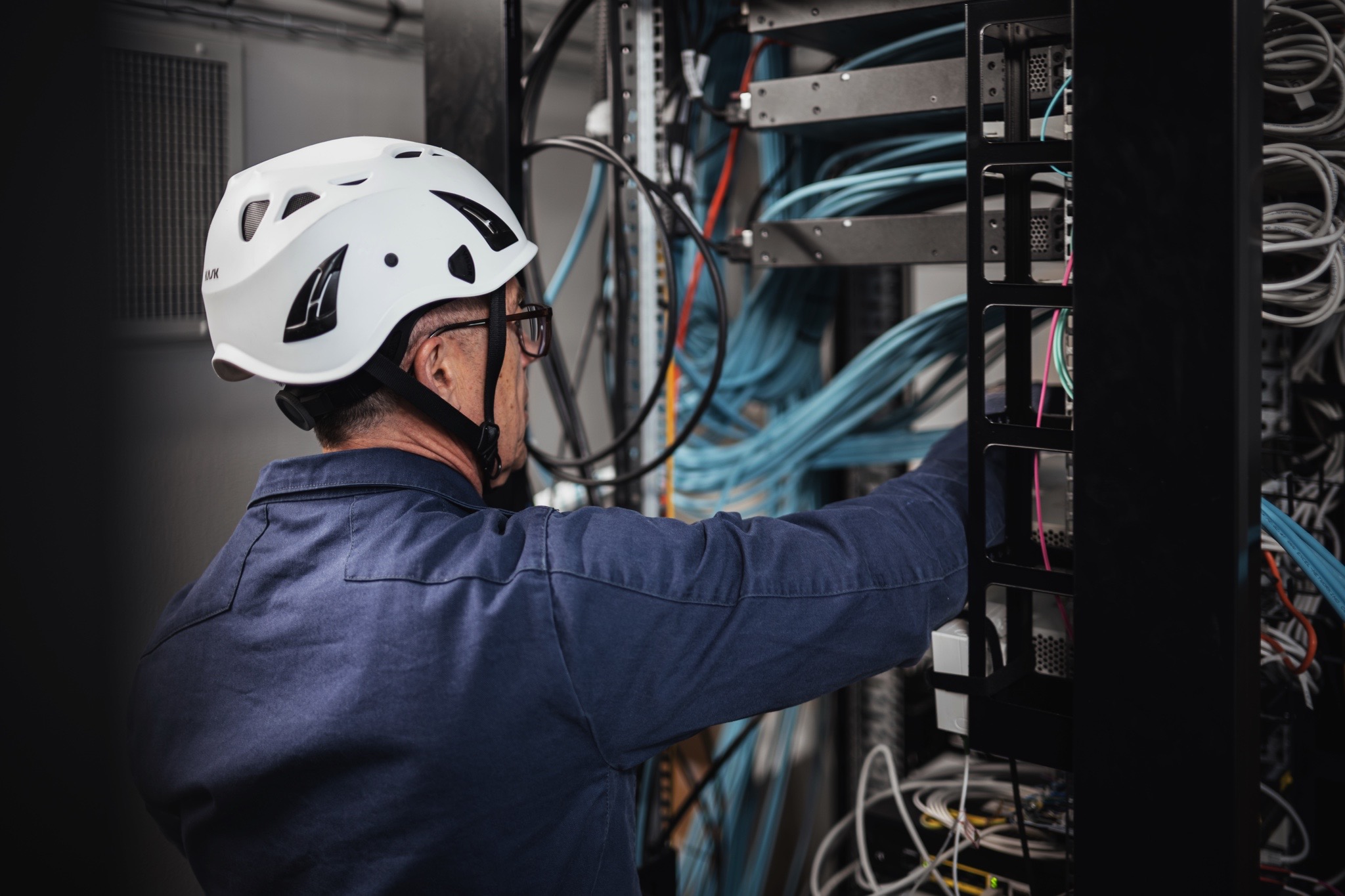 Technicien intervenant sur une baie informatique pour le raccordement et la maintenance des équipements réseau et télécoms.