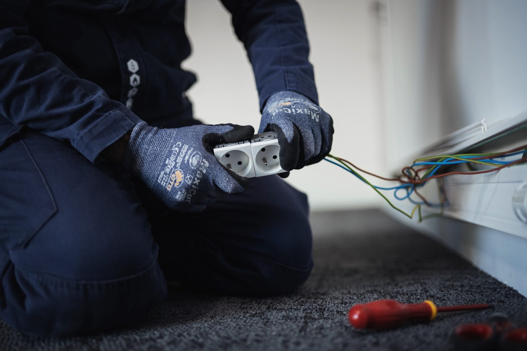 Électricien réalisant le câblage et le raccordement de prises électriques lors d’une installation électrique intérieure.