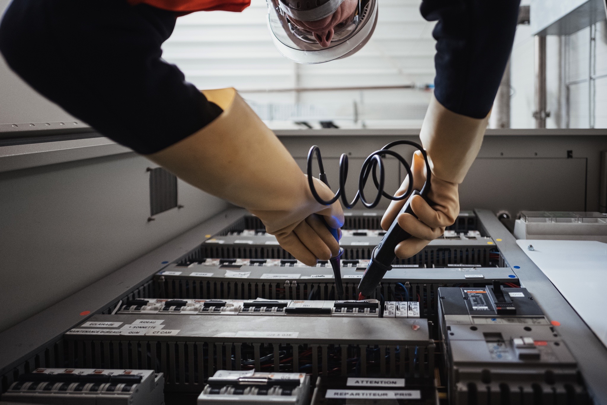 Technicien réalisant des mesures de contrôle sur un tableau électrique industriel à l’aide d’instruments de test dans le cadre d’une opération de maintenance.
