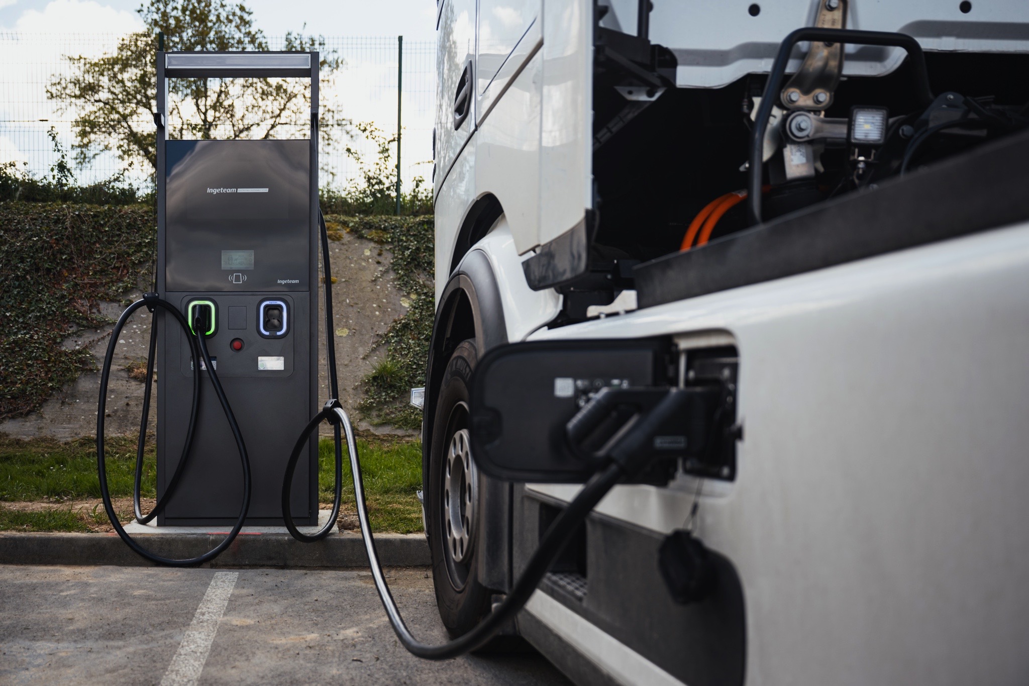 Véhicule utilitaire électrique en cours de recharge sur une borne IRVE installée sur un parking d’entreprise.